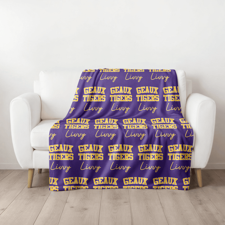 A personalized Blanket in Purple and Gold that says Geaux Tigers with a script font.