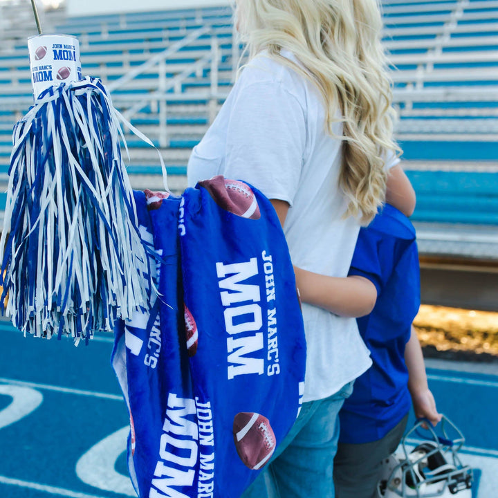 A Mom holding her bleacher blanket and matching tumbler walking her son after the big game. 