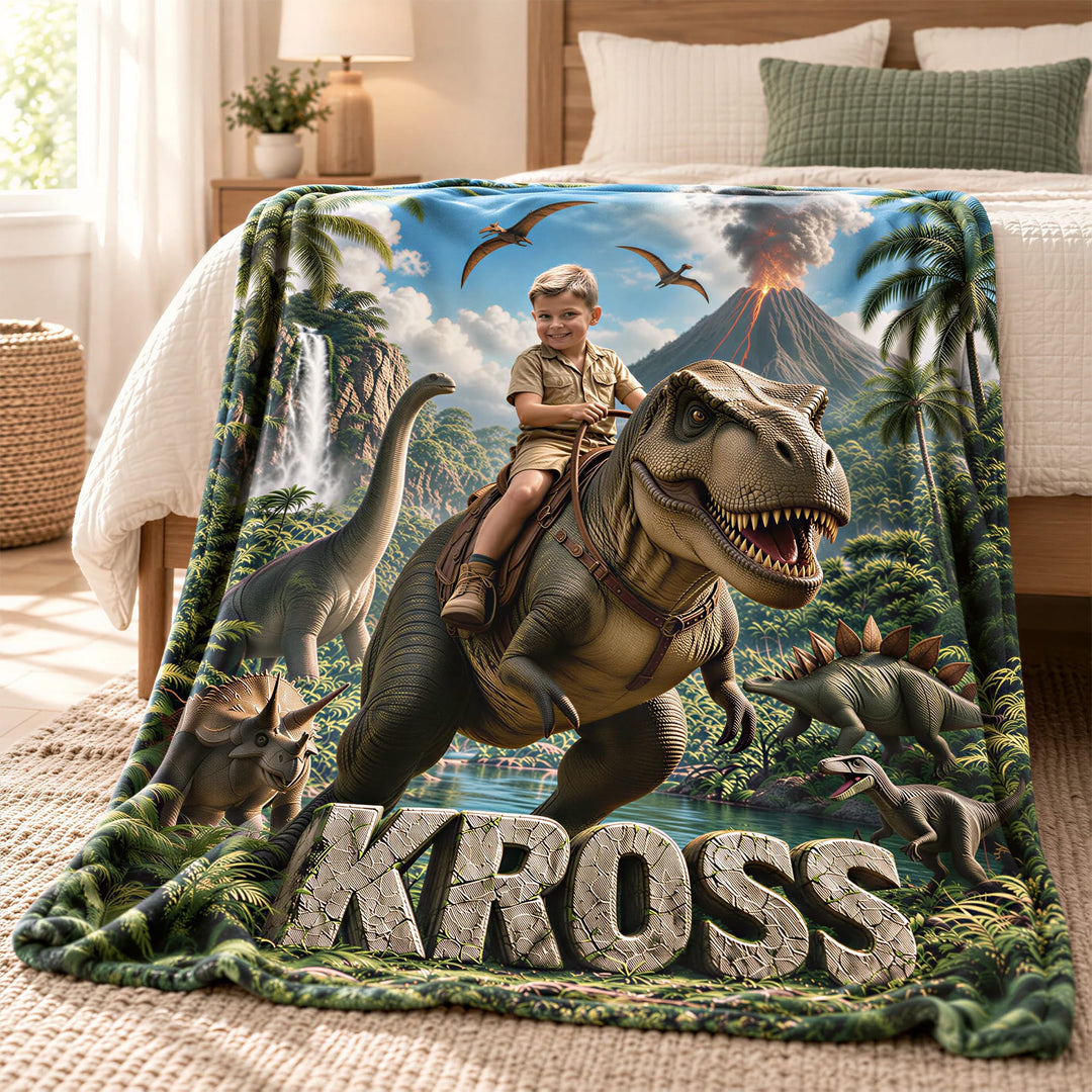 Personalized dinosaur blanket draped over a child's bed, showing a boy riding a T. rex with a volcano and waterfall behind