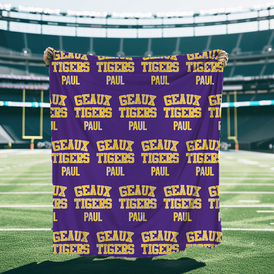 A personalized Blanket in Purple and Gold that says Geaux Tigers with a block font.