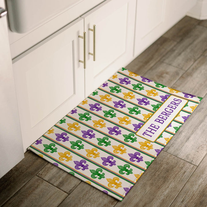 Personalized Mardi Gras fleur-de-lis welcome mat with purple, green, and gold stripes, customized with family name, placed at a kitchen sink.